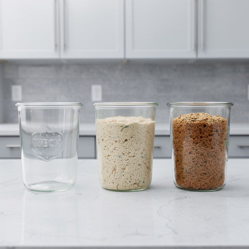 Drei Weckgläser – eines leer, eines mit heller glutenfreier Brotbackmischung und eines mit dunkler Körnermischung – von broat, ohne Zusatzstoffe