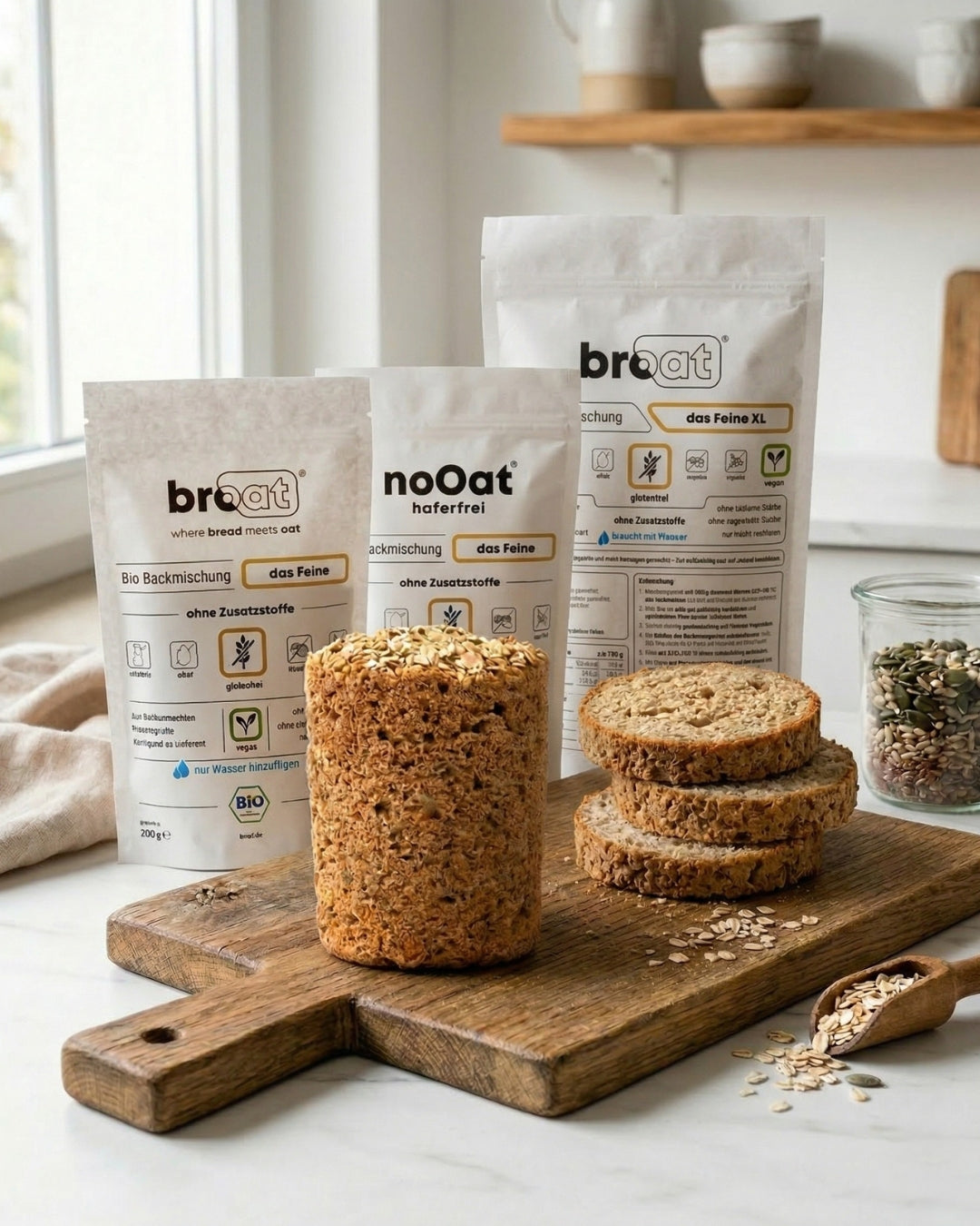broat und noOat Bio-Backmischungen das Feine auf Holzbrett mit frisch gebackenem glutenfreiem Brot, Weckglas und Holzlöffel in heller Küche – ohne Zusatzstoffe