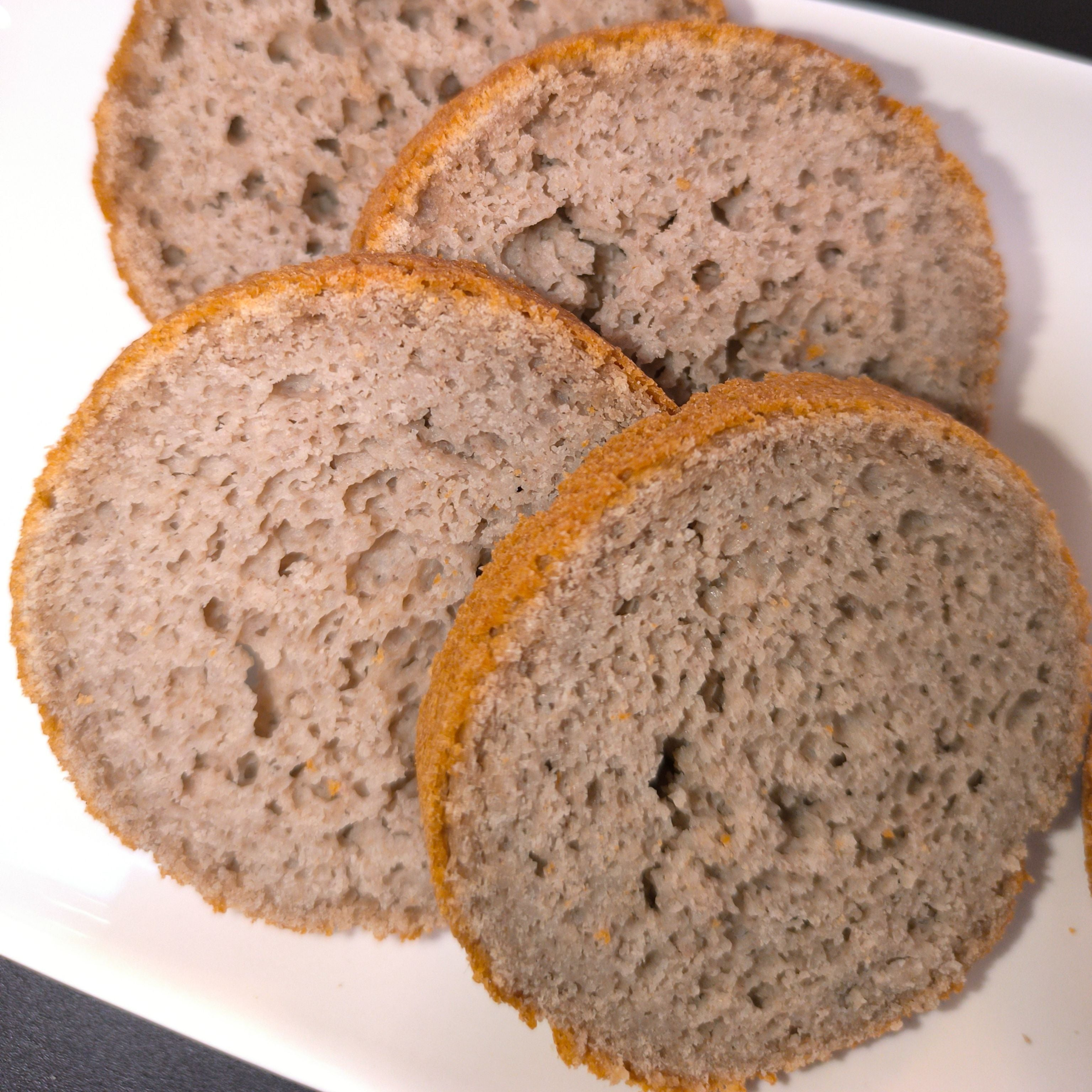 Drei Scheiben des fertig gebackenen noOat Brotes Sorte das Feine auf einem weißen Teller. Das glutenfreie Brot zeigt eine lockere, poröse Krume und eine hellbraune Kruste, hergestellt ohne Zusatzstoffe.